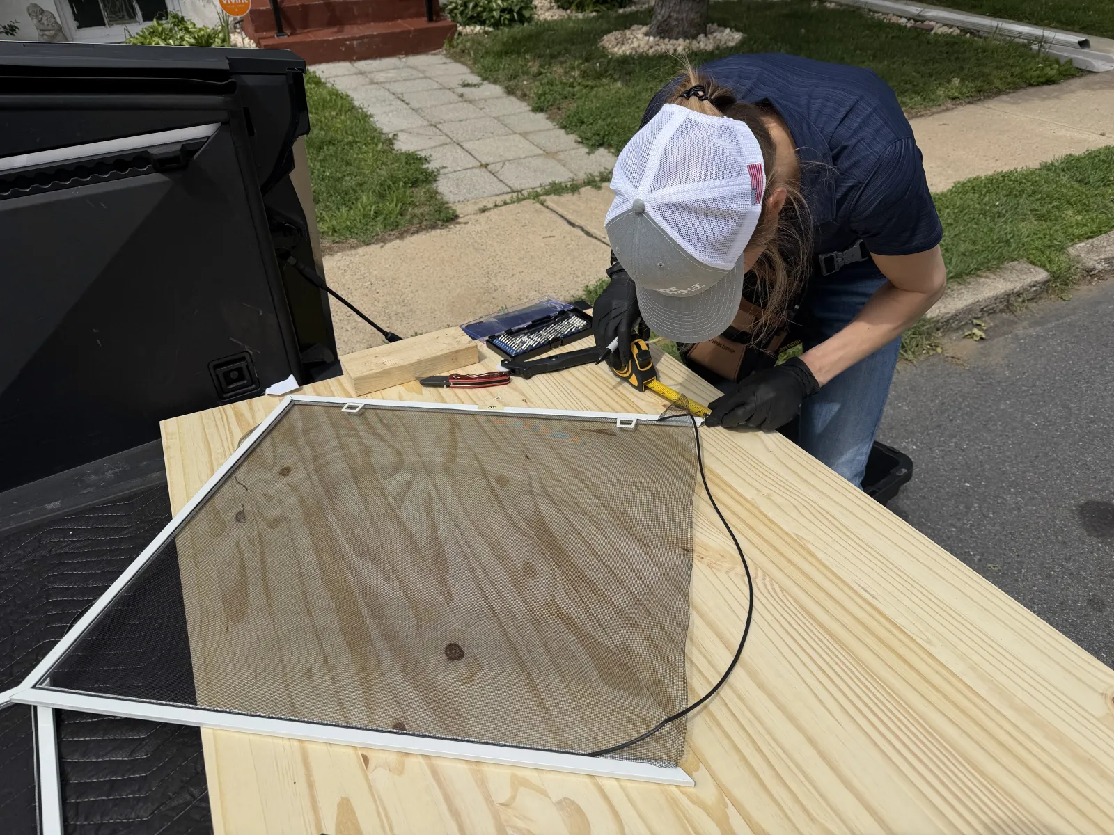 Technician repairing mesh in a residential window screen frame